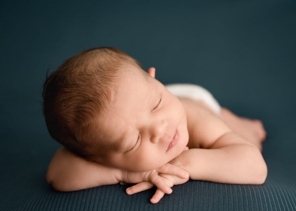 Easton Pennsylvania Newborn photographer forward facing baby sleeping during newborn photography session on teal background