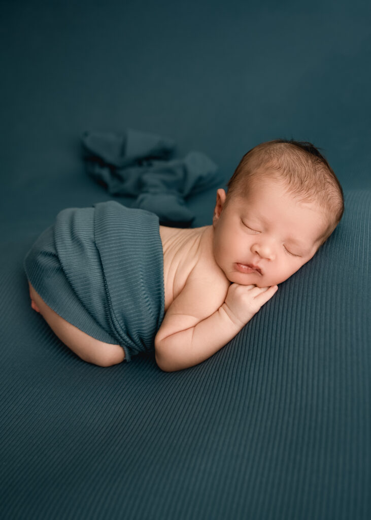Lehigh Valley Newborn photographer bum up pose baby sleeping during newborn photography session on teal background